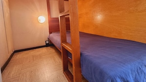 A small, compact room with a bunk bed, a single bed, and a small table. - Cozy studio with snow front view, close to chairlift and shops (Le Dévoluy)