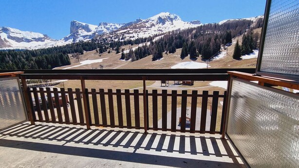 A balcony with a metal railing overlooking a mountainous landscape with snow-capped peaks and a forested valley. - Cozy studio with snow front view, close to chairlift and shops (Le Dévoluy)
