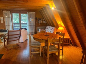 A cozy room with a wooden dining table, chairs, a sofa, and a lamp.