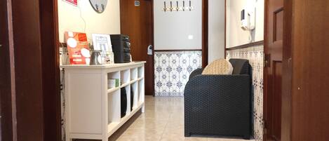 Enter a welcoming hallway with a reception desk, wicker sofa, and small table.