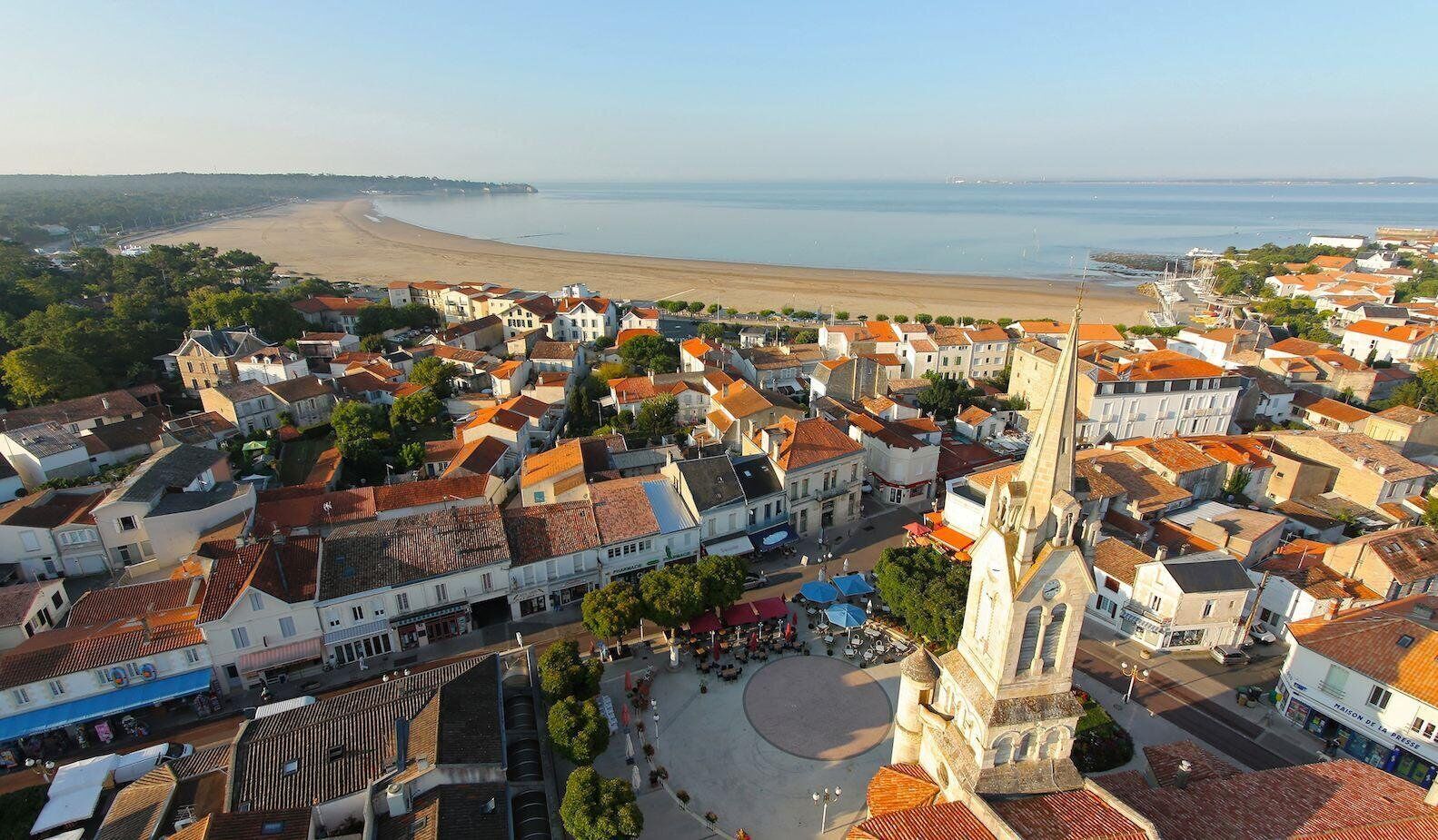 A coastal town with a prominent church, narrow streets, and a beach in the background.