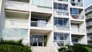A multi-story building with a modern architectural design, featuring balconies, large windows, and a staircase leading to the entrance. - Studio Face mer et Proche Marché Pornichet (Pornichet)