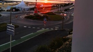 A sunset view from a balcony overlooking a roundabout with directional signs, a white tent-like structure, and a road with traffic lights. - Studio Face mer et Proche Marché Pornichet (Pornichet)
