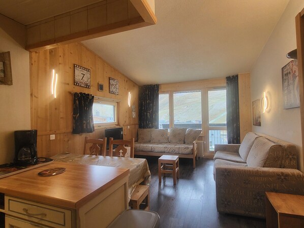 Une pièce chaleureuse avec un décor intérieur en bois, un canapé, une table à manger avec des chaises et un petit coin cuisine.