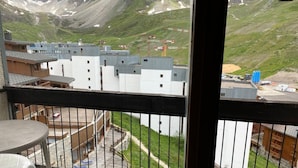 Un balcón con vista a un paisaje montañoso, una pequeña mesa y una silla.