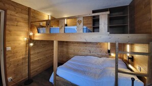 Habitación con literas, decoración de madera, un escritorio y un espejo.