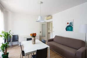 A modern living room with a white table, brown sofa, and a ceiling light.