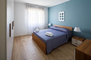 A bedroom with a bed, bedside tables, a lamp, a phone, and a wall art piece.