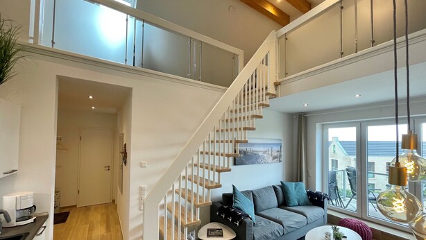 A modern living space with a staircase, a sofa set, and a dining area.