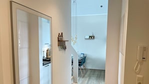 A hallway leading to a dining area with a kitchen visible in the background.