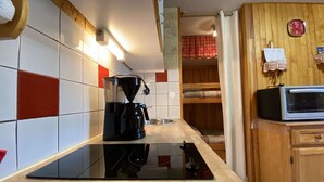 A kitchen with a black coffee maker, a microwave, and a wooden cabinet. - Cozy apt for 6, Praz-sur-Arly, free shuttle, parking, pets allowed (Praz-sur-Arly)