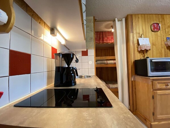 A kitchen with a black coffee maker, a microwave, and a wooden cabinet.