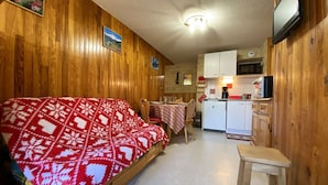 A compact room with a bed, a small table, a kitchenette, and a television. - Cozy apt for 6, Praz-sur-Arly, free shuttle, parking, pets allowed (Praz-sur-Arly)