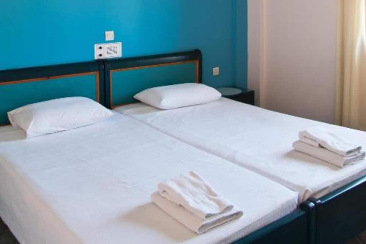A twin bed with white linens and a small bedside table.