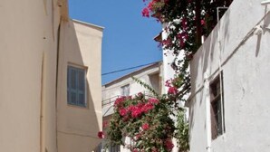 Una calle estrecha flanqueada por edificios, algunos con balcones y flores.