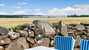 En stenvæg med udsigt til en sø og fjerne træer.
