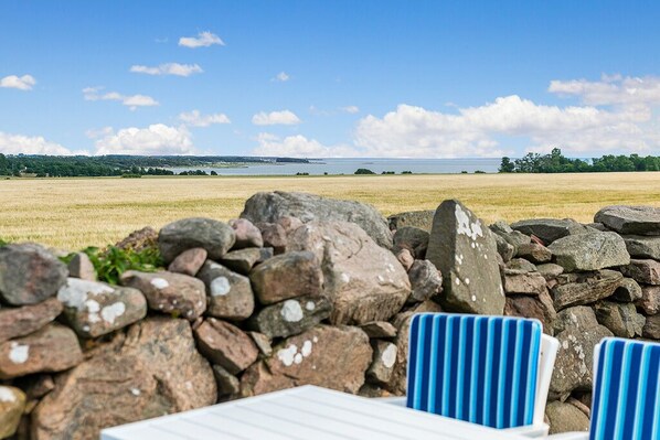 A stone wall with a view of a lake and distant trees.