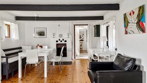 En moderne stue med en sort lædersofa, hvide møbler og en pejs.