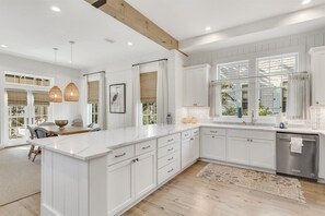 Une cuisine moderne avec des meubles blancs, un îlot central et des luminaires suspendus.