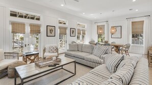 A spacious living room with a large striped sofa, a coffee table, and a ceiling fan. - Watercolor Resort|Close To Pool | 6 Pass Golf Cart (Santa Rosa Beach)