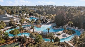 Un resort con varias piscinas, palmeras y sillones de descanso.
