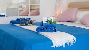Un lit bien fait, avec une literie bleue, une serviette enroulée et un panneau indiquant « MAISON ».