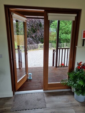 A wooden door leading to a covered outdoor area with a gravel path and a white fence. - Oak Tree Cabin (Fivemiletown)