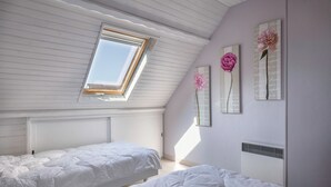 A bedroom with two beds, a skylight, and decorative wall art. - 300m beach, lovely house, 6 adults 1 child (Sarzeau)
