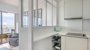Uma cozinha moderna com armários brancos, forno embutido e cafeteira sobre a bancada.