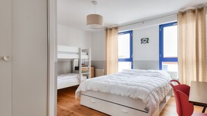 Un dormitorio con una cama litera, una cama individual, un escritorio y una silla.