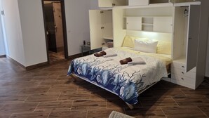 Een slaapkamer met een bed, een inbouwkleerkast en een klein nachtkastje.