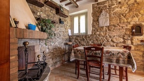 A rustic dining area with stone walls, a fireplace, and a table set for two.