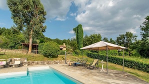 A swimming pool with lounge chairs and a pergola.