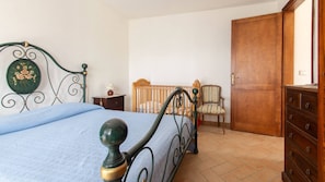 A bedroom with a bed, a wooden wardrobe, a chair, and a nightstand.