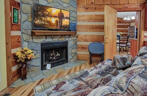 Una sala acogedora con chimenea de piedra, televisor montado arriba y un sofá cómodo.