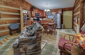 L’intérieur d’une cabane comprend un espace de vie, une table à manger, une cuisine et des murs en bois.