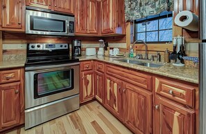 Una cocina con armarios de madera, electrodomésticos de acero inoxidable, encimeras de granito y un ventanal con vistas.