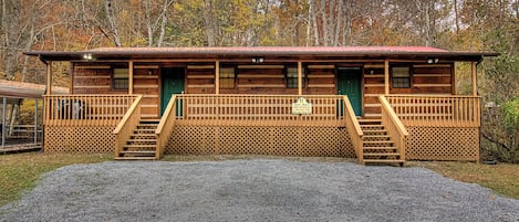 Une cabane en bois dotée d’un porche et d’un escalier menant à l’entrée.
