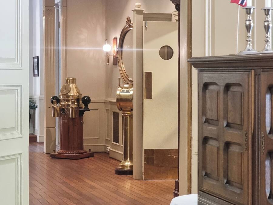 A room with wooden flooring, a wooden cabinet, and a brass elevator.