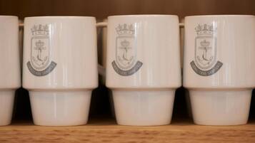 A row of white ceramic mugs with embossed logos, arranged on a shelf.