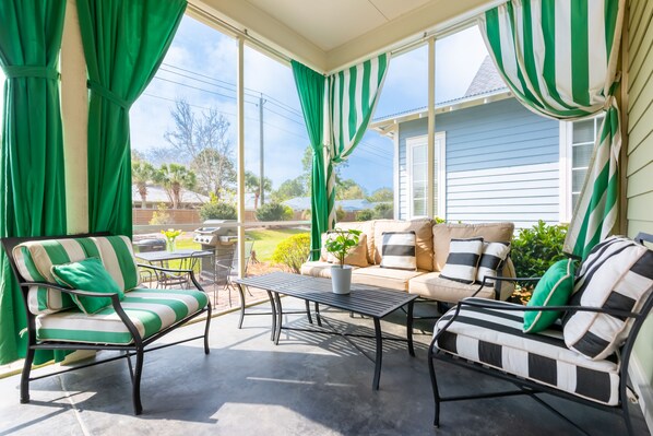 A covered patio with a sofa, chairs, and a table.