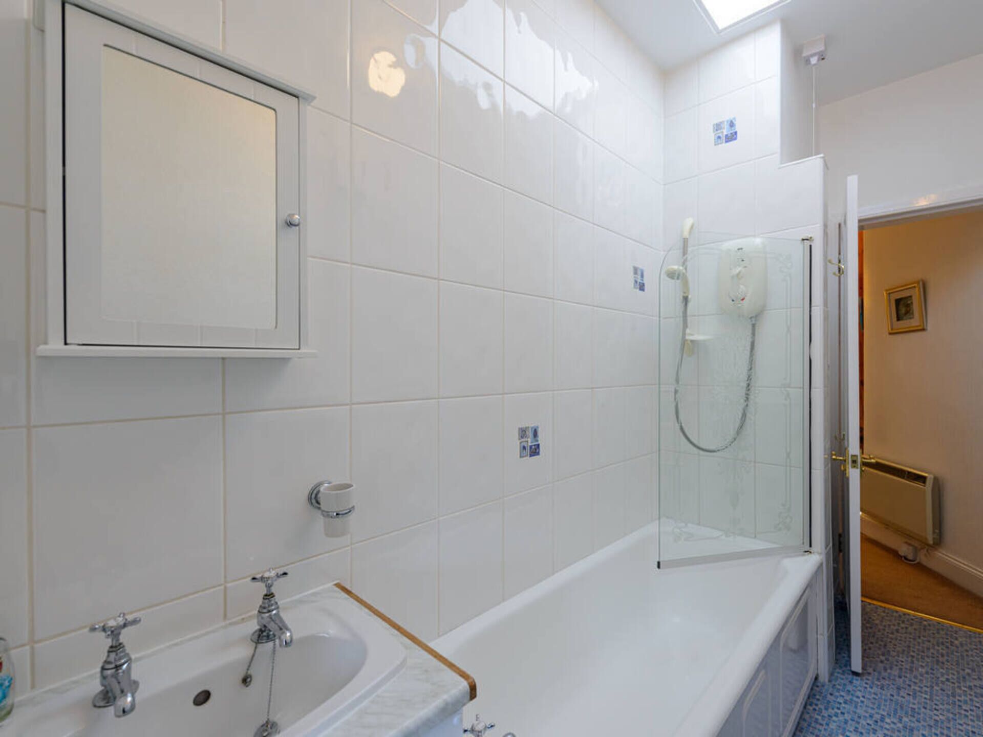 A bathroom with a bathtub, a sink, a glass-enclosed shower, and a mirror above the sink.