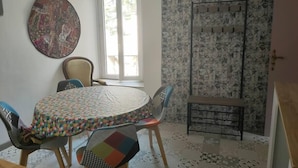 Un comedor con una mesa redonda, sillas y un mantel estampado. Se observa una gran obra de arte abstracta en la pared, una ventana con vistas y una pared decorada.