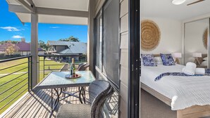 Varanda com mesa e cadeiras, cama com vista para o exterior e teto com luminária circular.