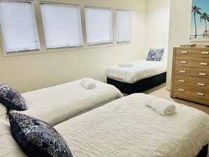 Ein Hotelzimmer mit zwei Betten, einer Holzkommode und einem Gemälde an der Wand.