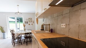 Una cucina moderna con un piano di lavoro in legno, elettrodomestici in acciaio inossidabile e un'area pranzo con tavolo e sedie.