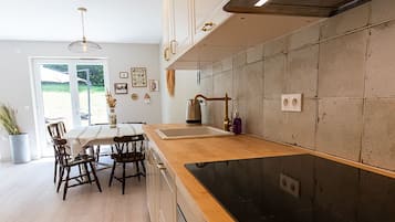 Een moderne keuken met een houten aanrecht, roestvrijstalen apparatuur en een eethoek met een tafel en stoelen.