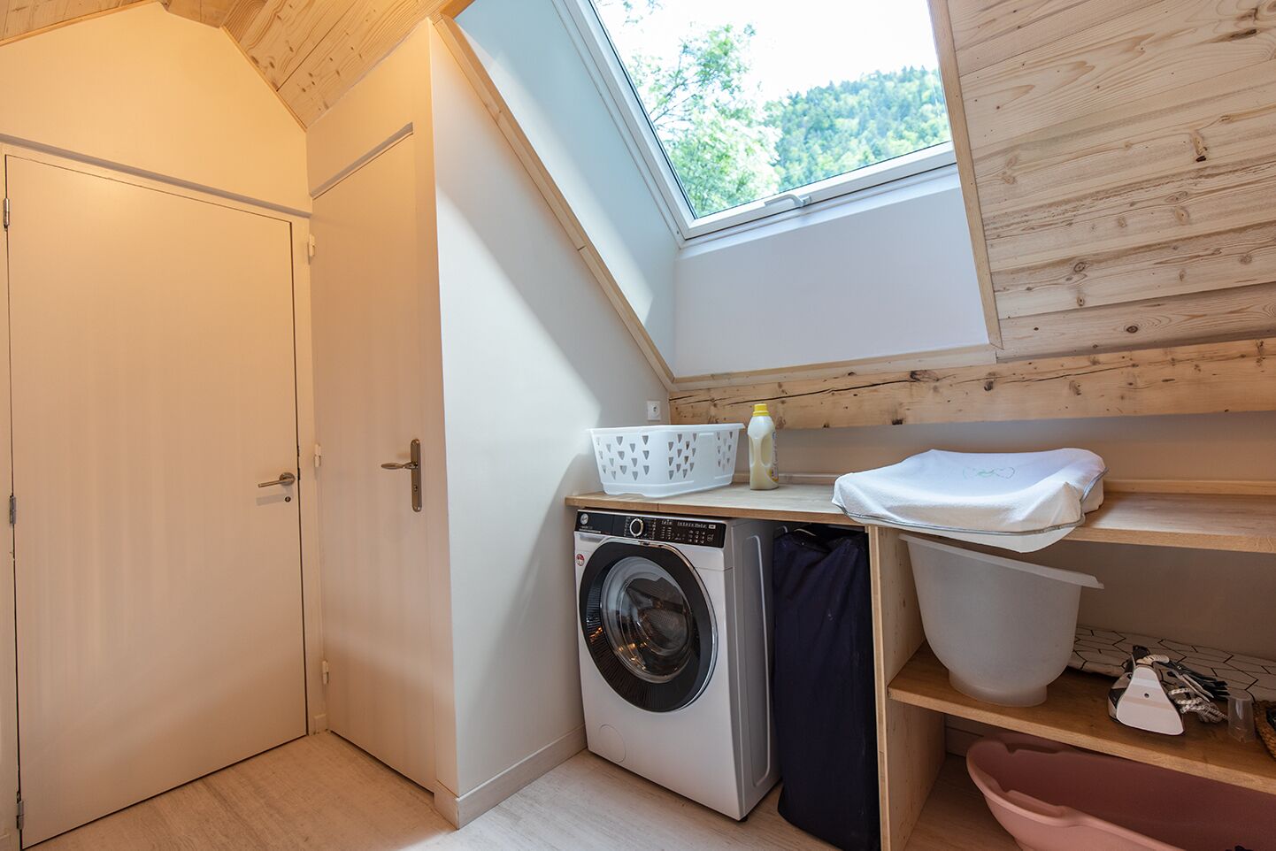 Une petite buanderie équipée d’un lave-linge, d’un étendoir et d’un puits de lumière.
