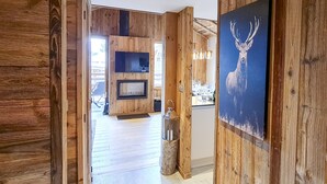 Ein hölzerner Innenbereich mit einem Flur, der zu einem Essbereich führt, mit einem Wandfernseher und einem Bild von einem Hirsch.