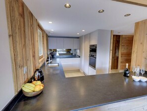 Een moderne keuken met een centraal eiland, ingebouwde apparatuur en uitzicht op de eetruimte.